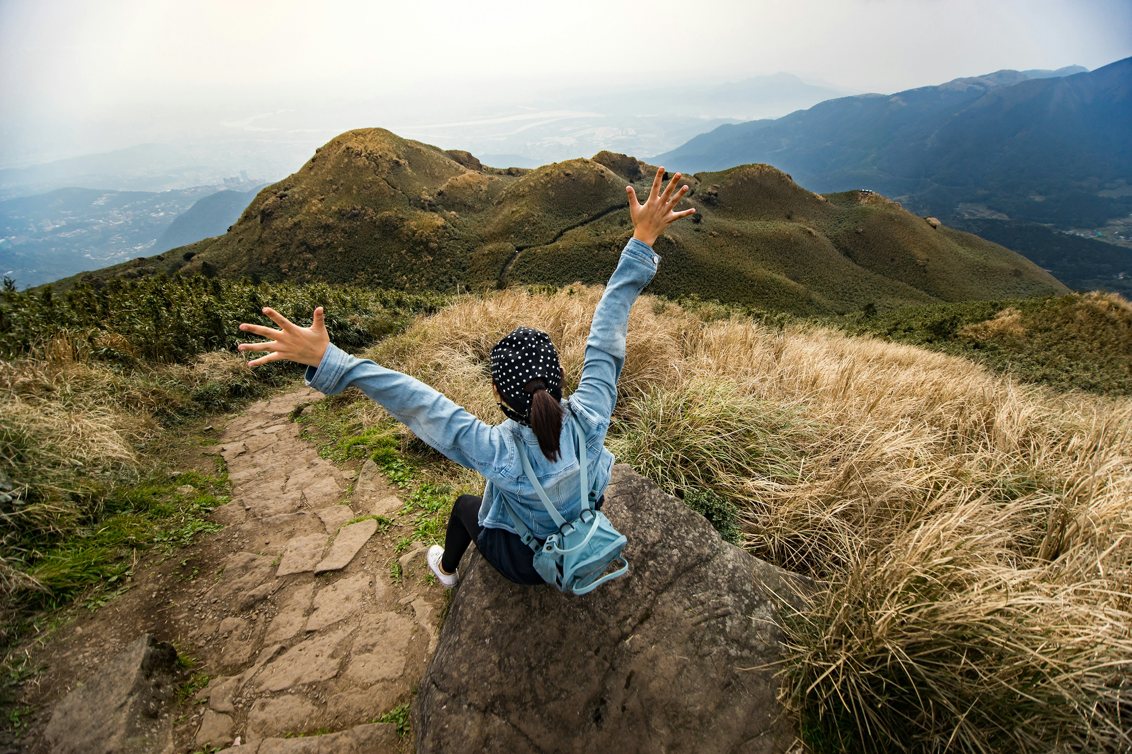 Traveller sitting at the summit of Mt Qixing, the highest mountain near Taipei