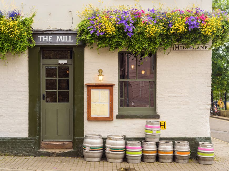 The facade of an old pub on Mill Place in Cambridge, with flowers and barrels outside