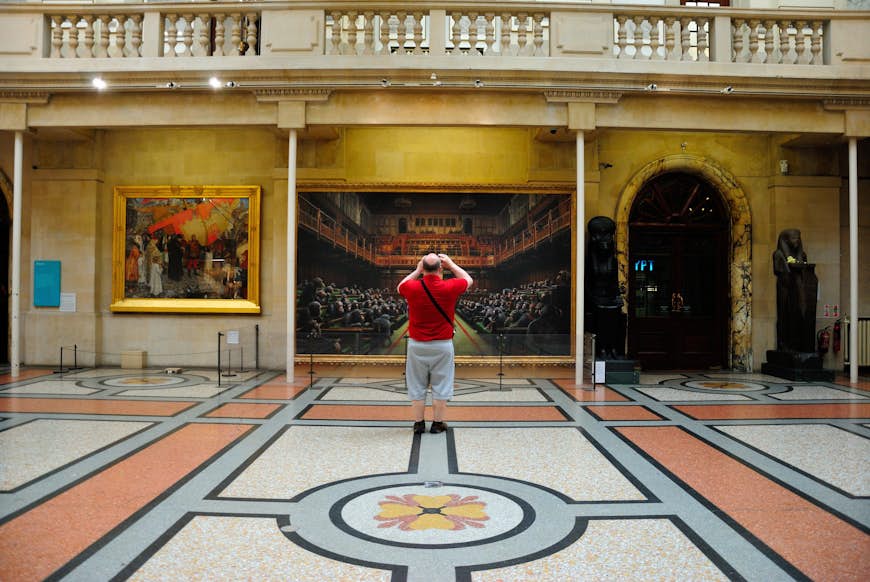 Мужчина фотографирует произведение искусства в Бристольском городском музее и художественной галерее, Бристоль, юго-запад, Англия, Великобритания.