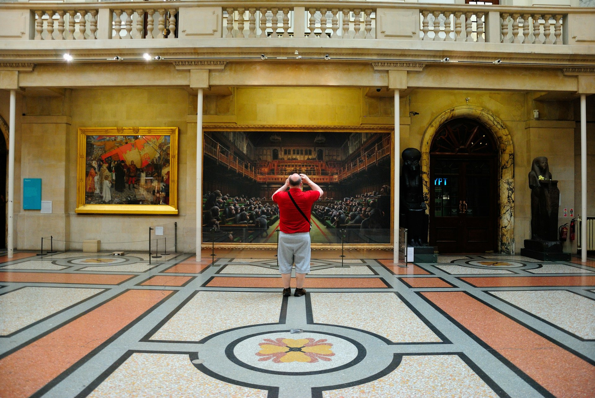 A man takes a picture of an art piece inside the Bristol City Museum & Art Gallery, Bristol, Southwest, England, UK