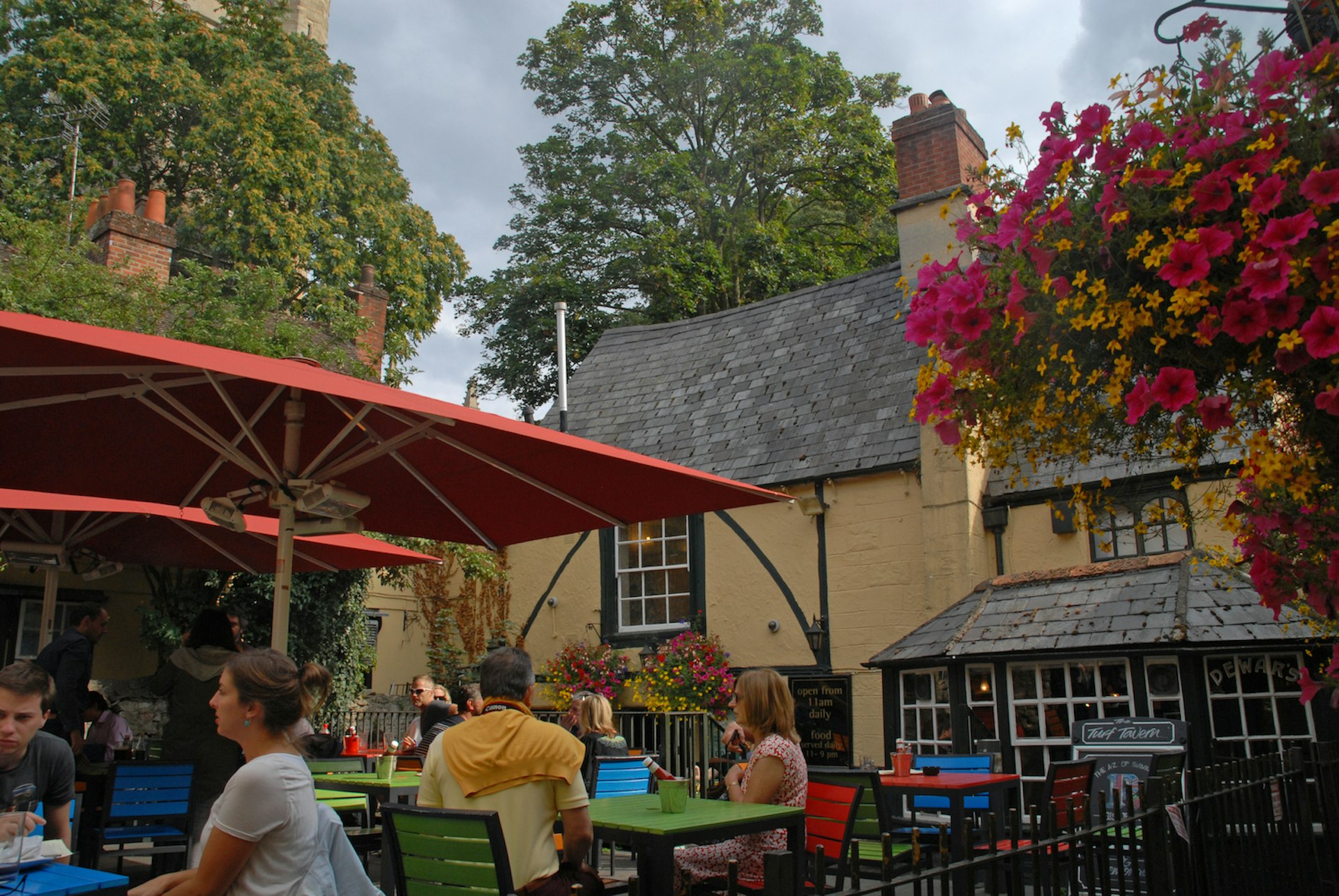 People enjoy drinks at outdoor tables in the beer garden of the Turf Tavern pub, Oxford, Oxfordshire, England, United Kingdom