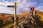 A woman crossing a stile on the Pennine Way, English Countryside walk.UK; Shutterstock ID 275558420; your: Brian Healy; gl: 65050; netsuite: Lonely Planet Online Editorial; full: Best hikes in the UK
