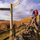 A woman crossing a stile on the Pennine Way, English Countryside walk.UK; Shutterstock ID 275558420; your: Brian Healy; gl: 65050; netsuite: Lonely Planet Online Editorial; full: Best hikes in the UK