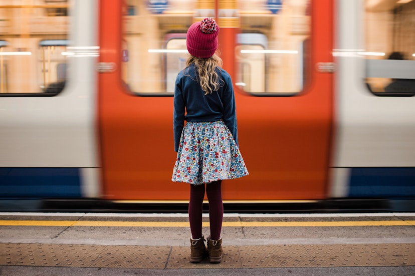 girl stood waiting for a train on the platform in London