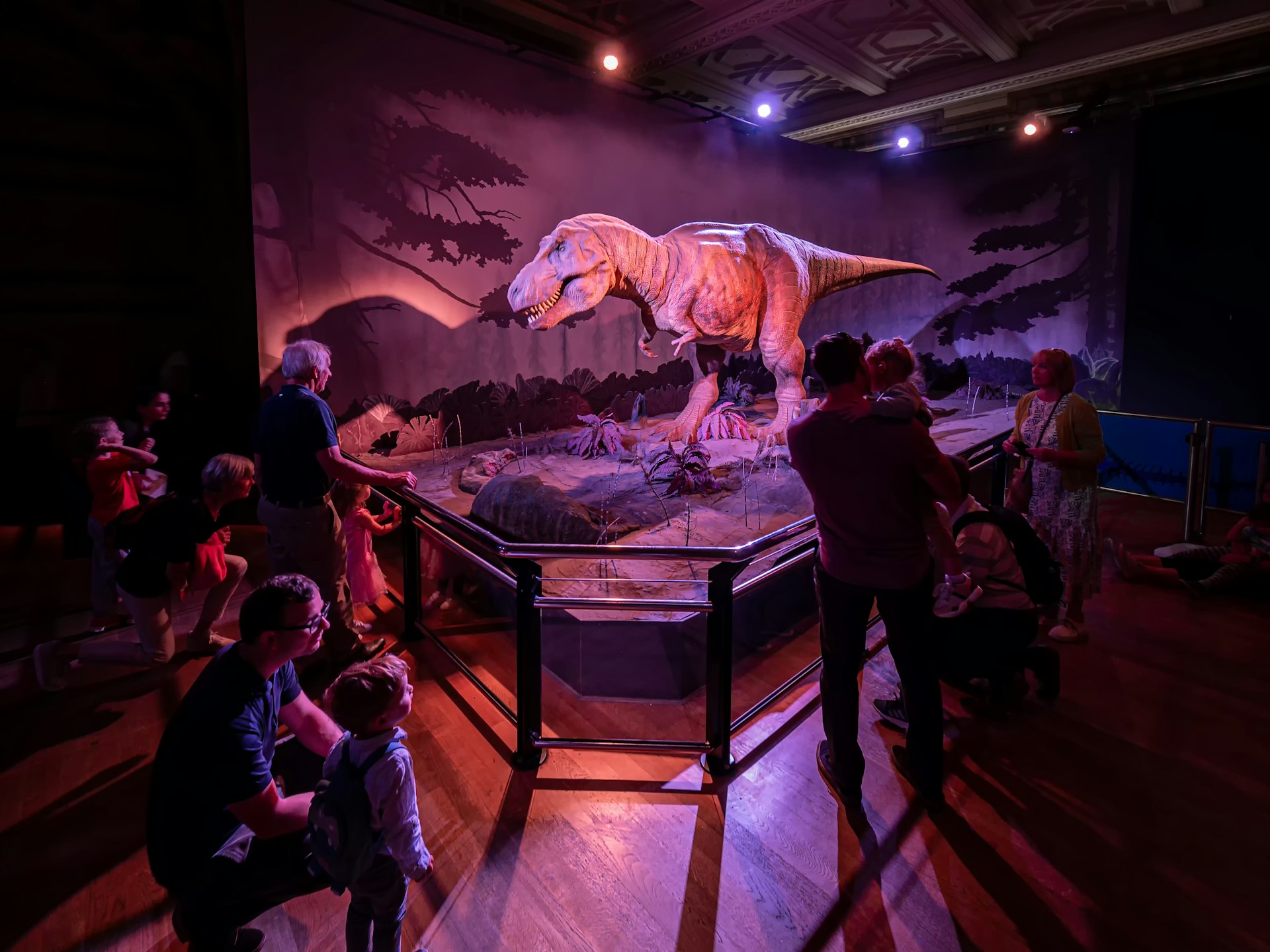 An life-size animatronic T-Rex has everyone's attention in a low-lit room at London's Natural History Museum