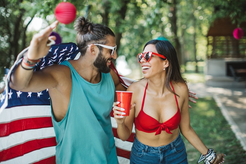 Friends celebrating forth of July. It is summer and they are dancing, singing and having fun together. Holding American flag.