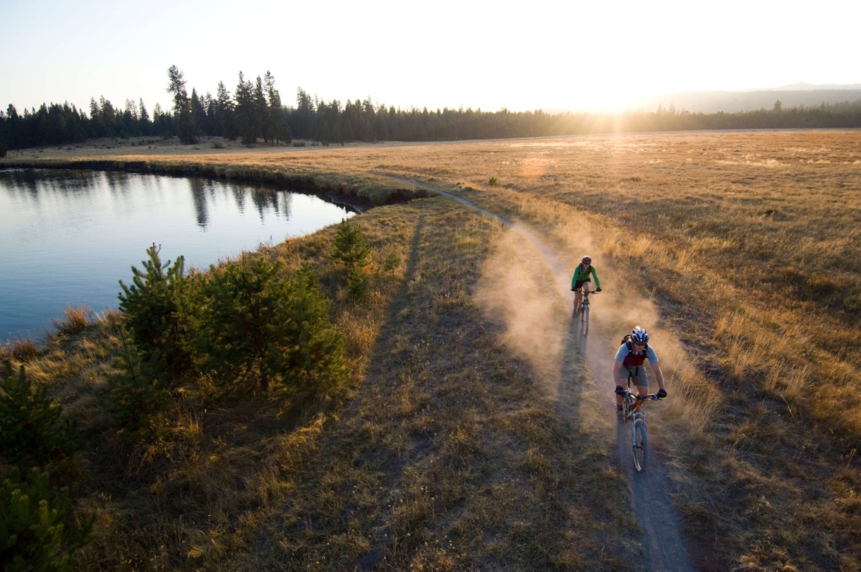 USA, Oregon, Bend, two cyclists on trail by river - stock photo