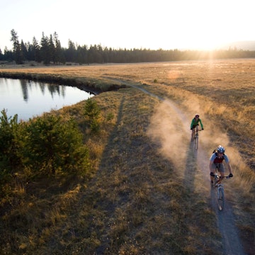 USA, Oregon, Bend, two cyclists on trail by river - stock photo