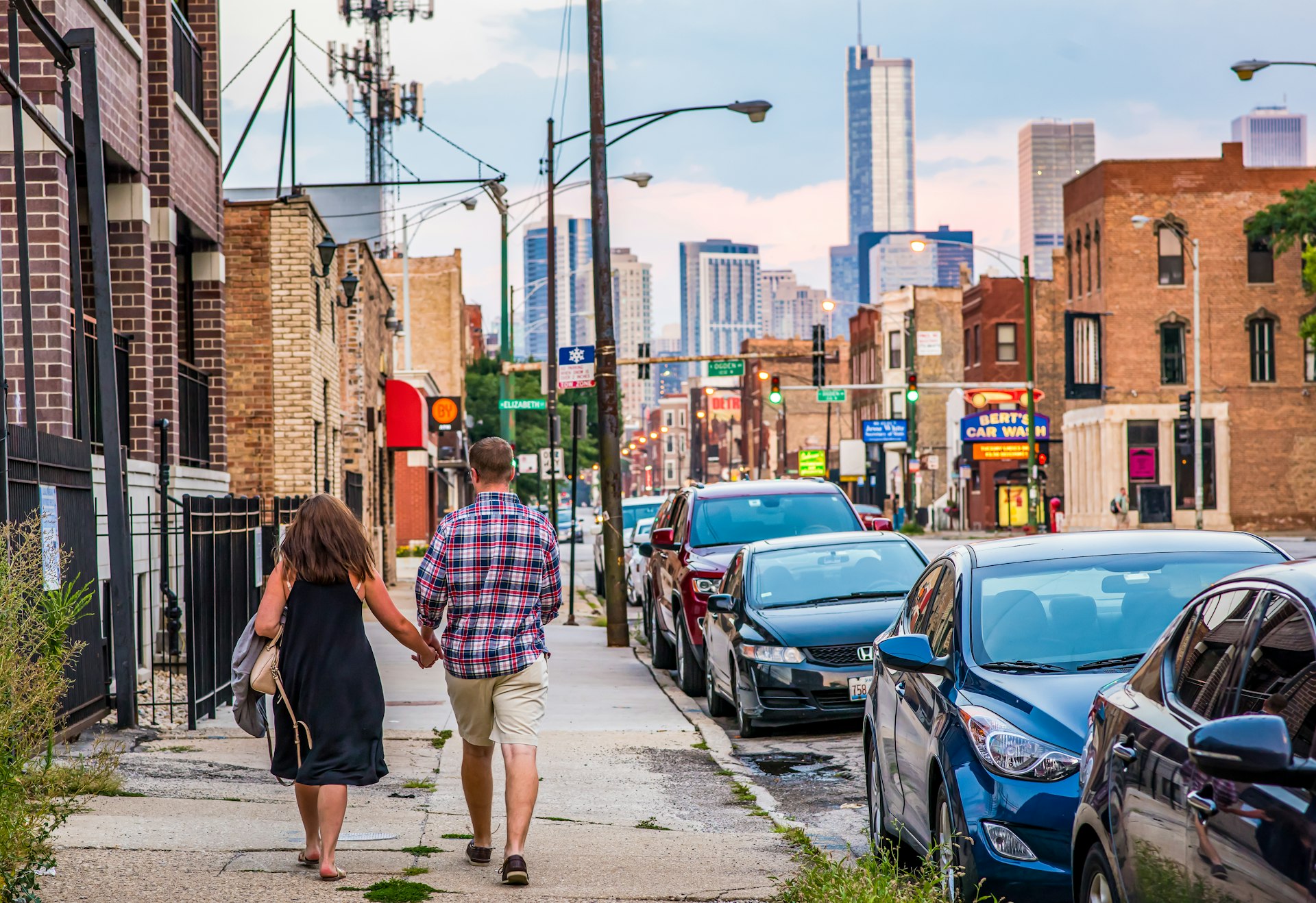 Young couple walk down a street towards a city with skyscrapers