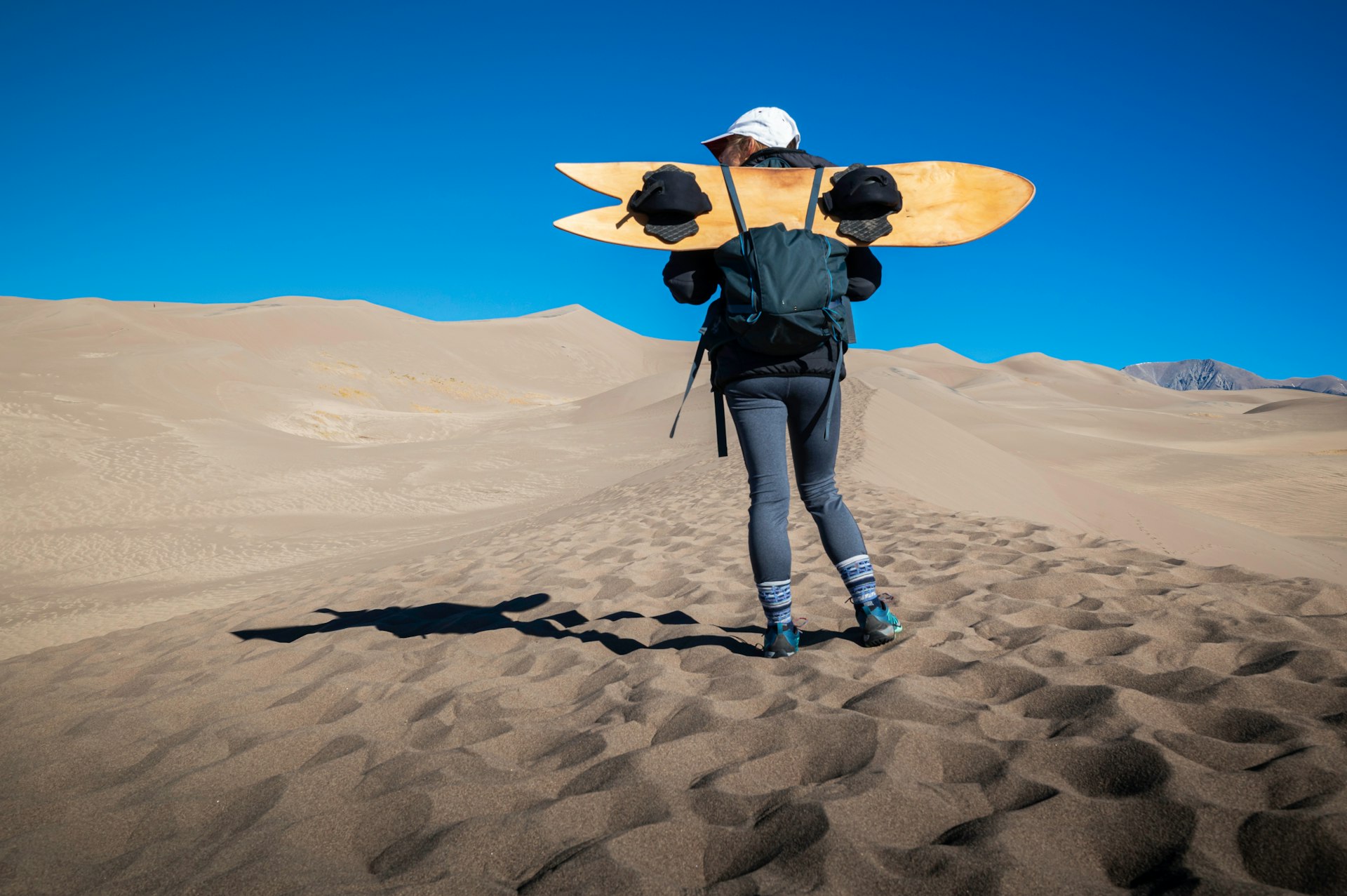 A female holds a sand board at Great Sand Dunes National Park, Colorado, USA