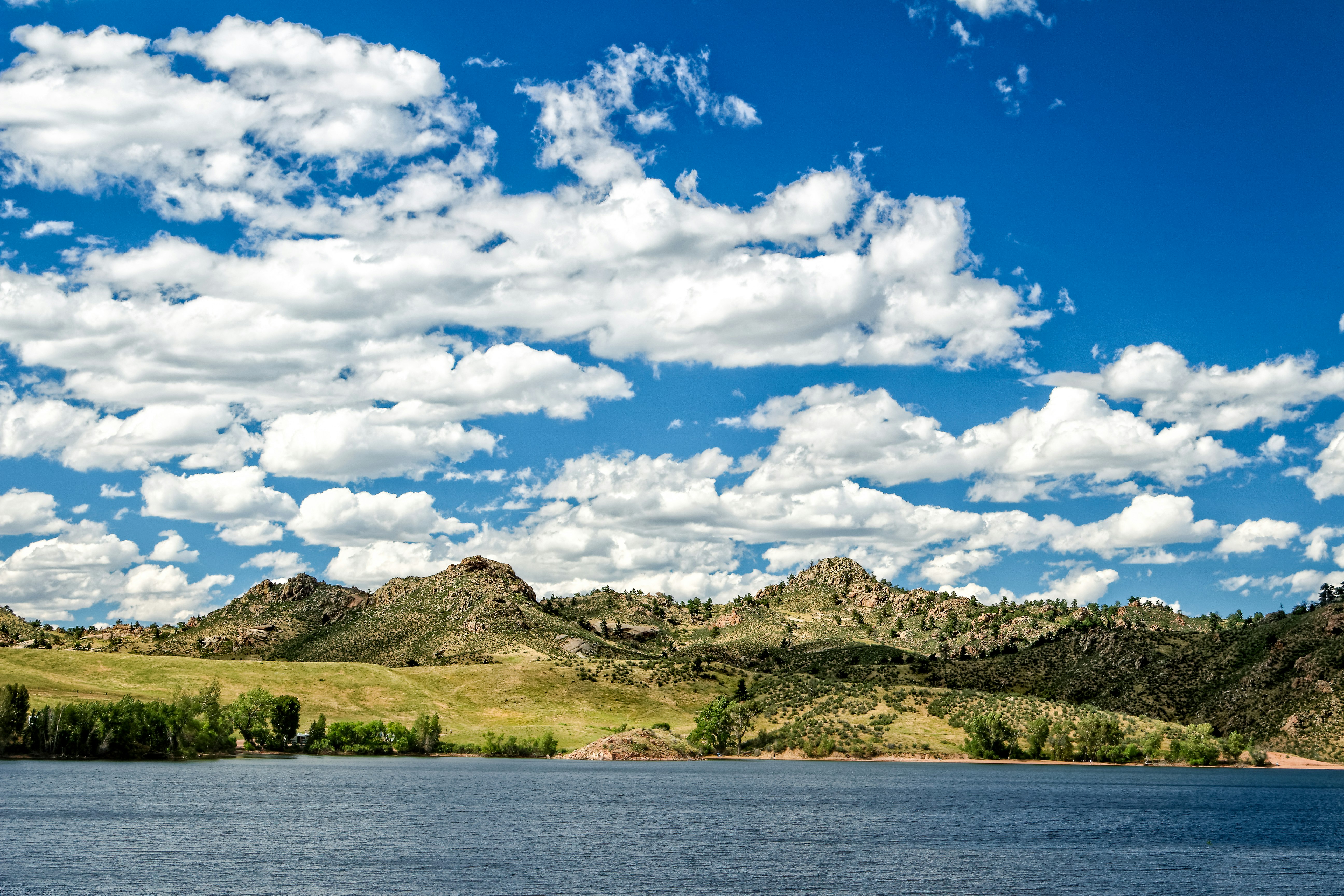 Crystal Lake glitters in the sun against a grassy series of hills at Curt Gowdy Park, Wyoming