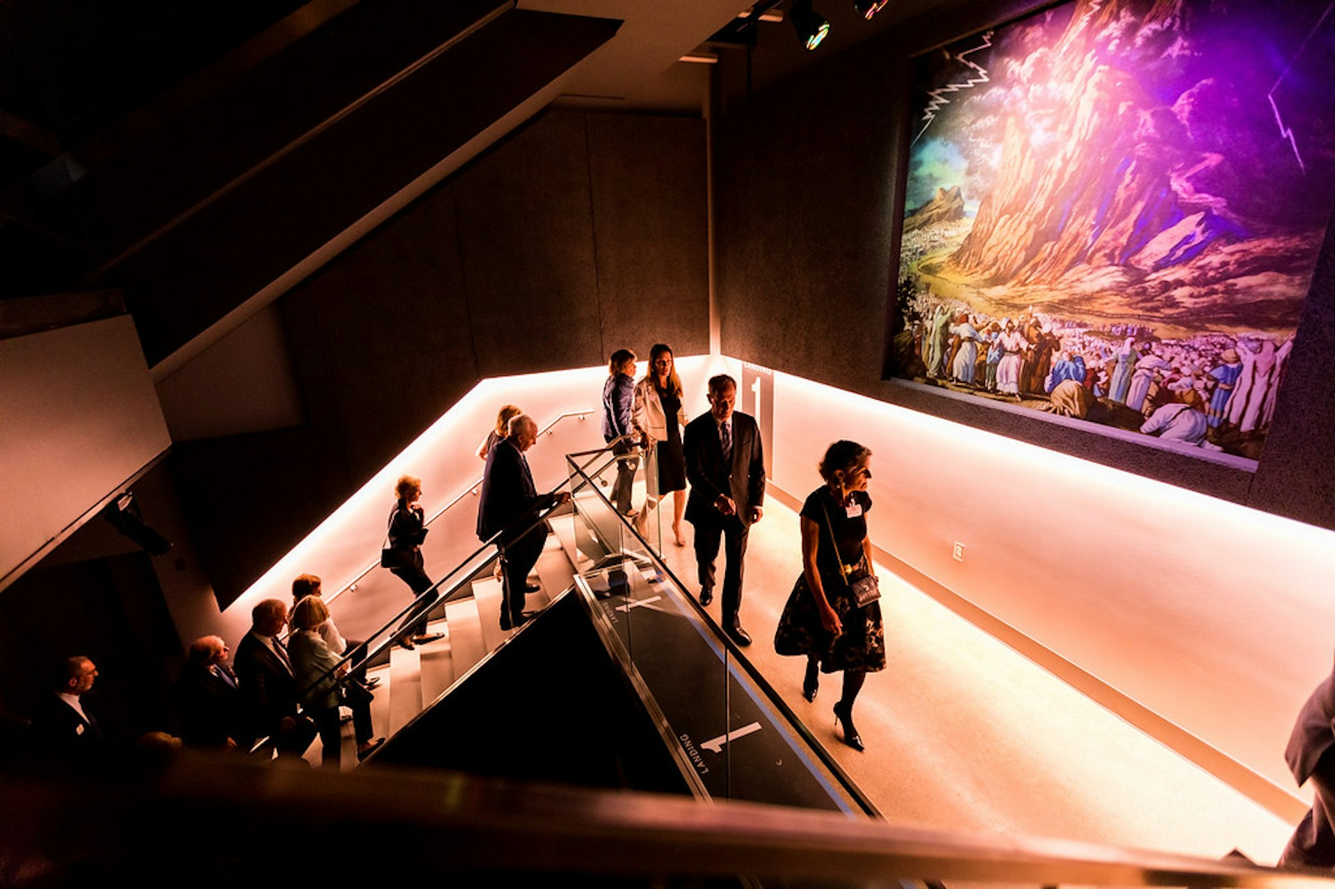 People walking up purple-lit stairs at the Dallas Holocaust and Human Rights Museum 