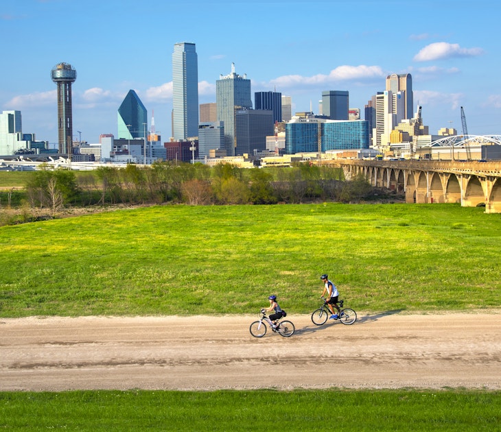 Cyclists on the bike trail in Trinity River Park with a backdrop of the Dallas skyline