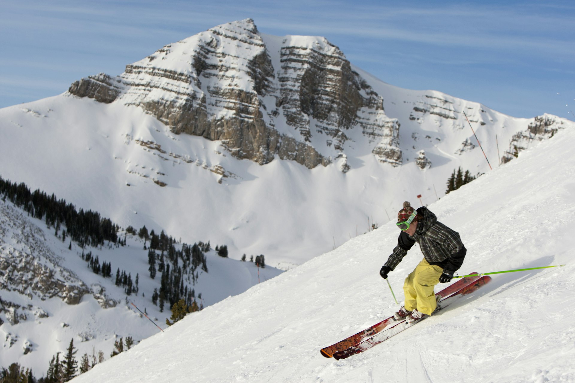 A person skis down a snowy slope with a rocky mountain peak in the background. Jackson Hole, Wyoming