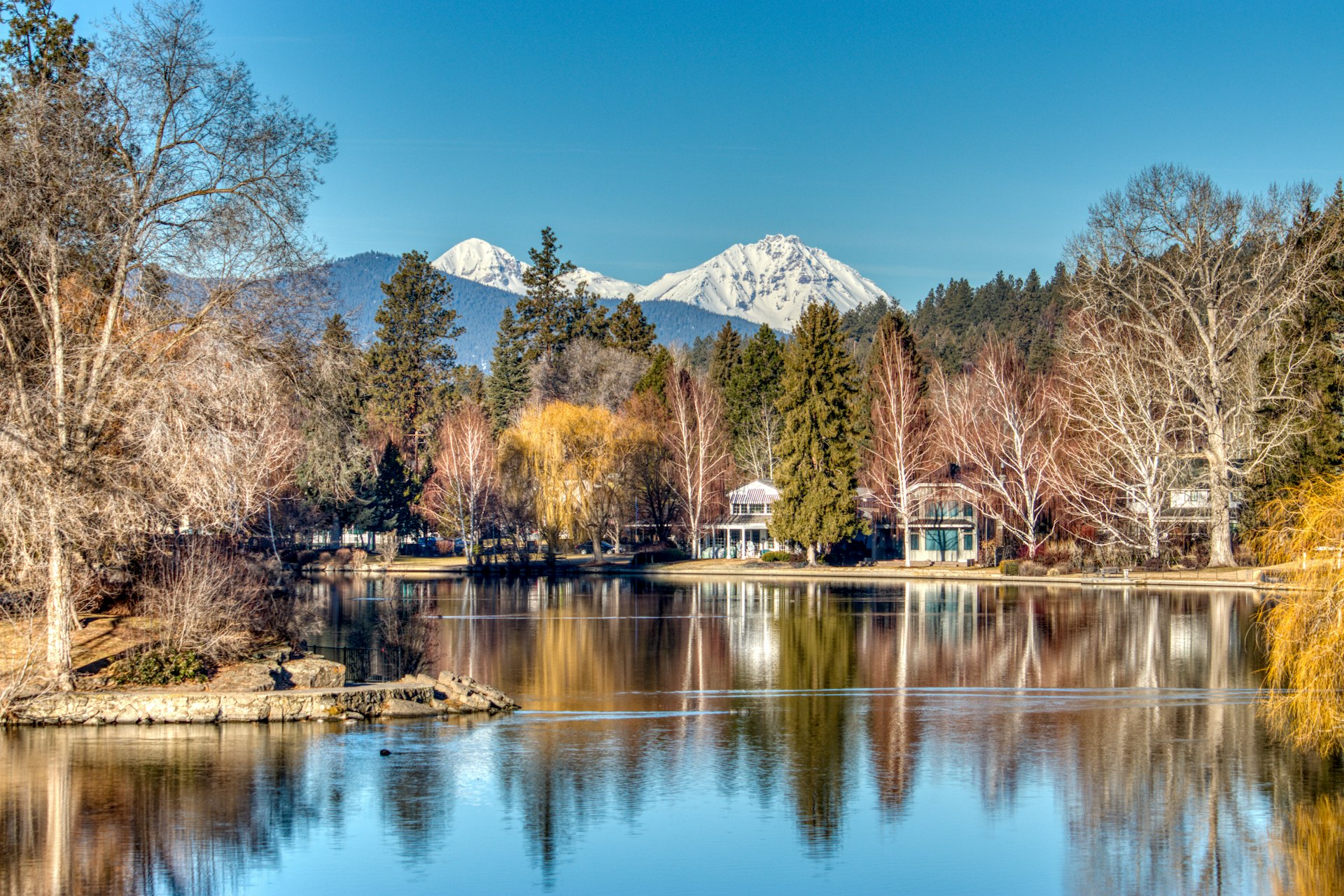 A view of homes around Mirror Pond with snowy mountains in the distance in Bend, Oregon, Pacific Northwest, USA