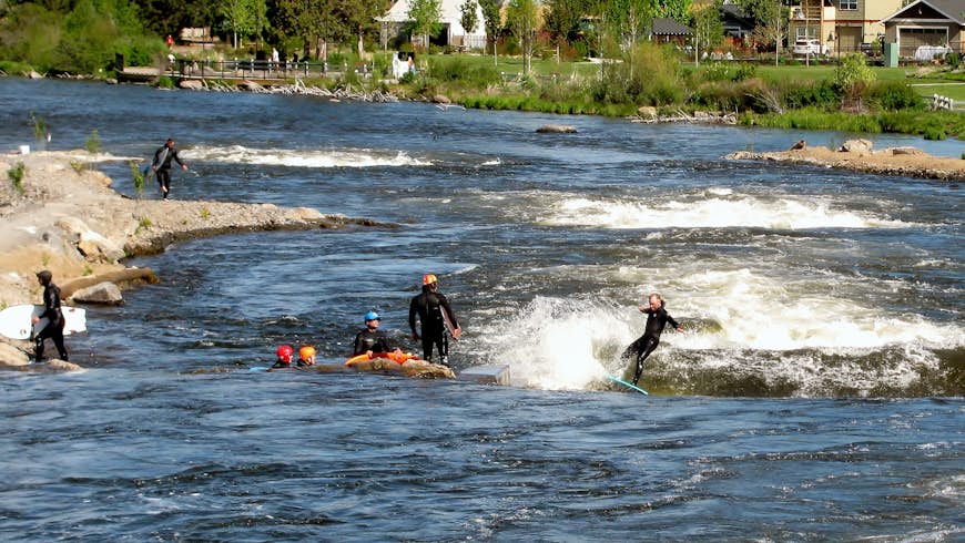 Group of people river surfing Bend Whitewater Park in the Deschutes River, Bend, Oregon, Pacific Northwest, USA