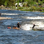 Deschutes River. Group of people river surfing in the whitewater park at Deschutes River. Bend, Oregon, USA.  May 21, 2017; Shutterstock ID 1192119136; your: Brian Healy; gl: 65050; netsuite: Lonely Planet Online Editorial; full: Best neighborhoods in Bend, OR