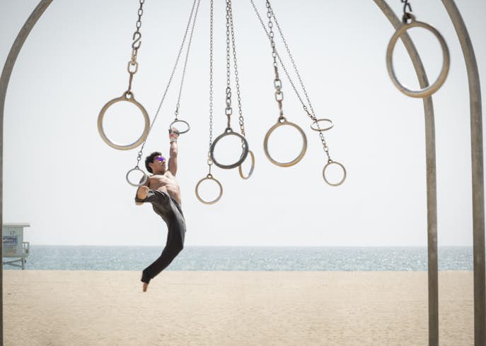 Man swings on suspended rings at an outside gym near Santa Monica beach