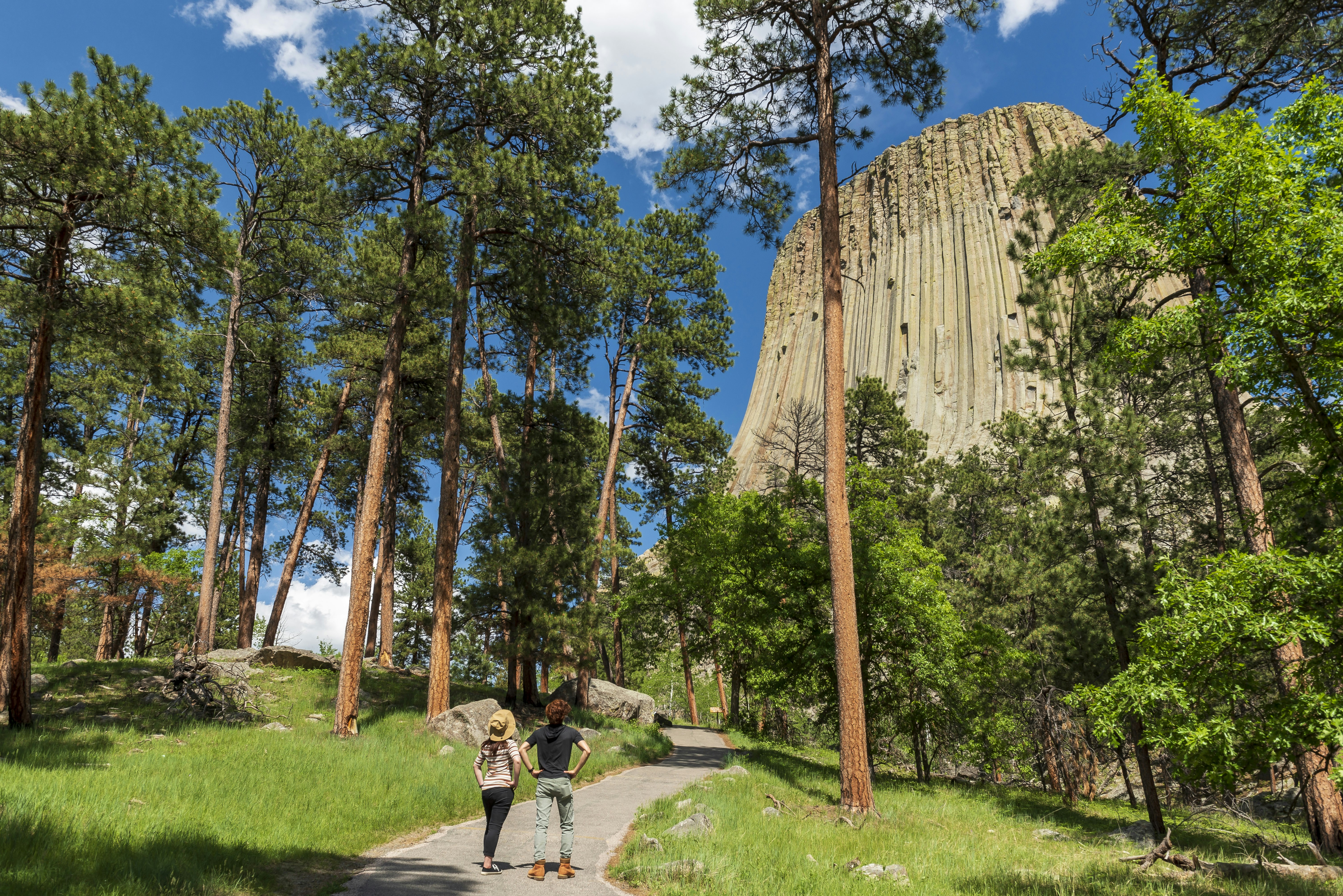 Two hikers look up at the tall rock formation known as Devils Tower in Wyoming, United States