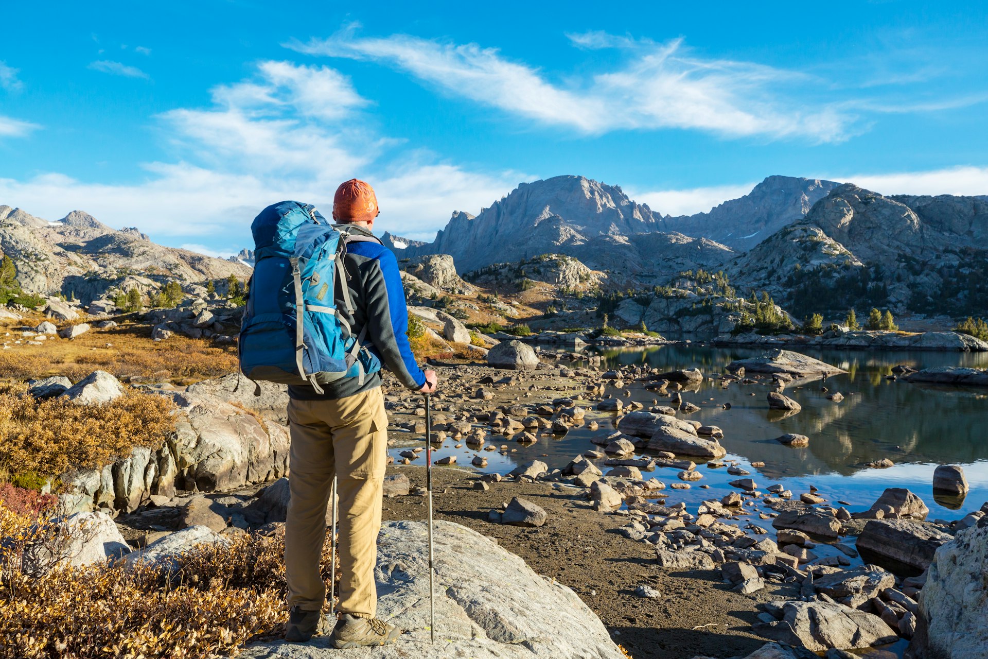 A backpacker seen from behind taking in a view of boulders and rocky mountains in the Wind River Range, Wyoming, The West, USA
