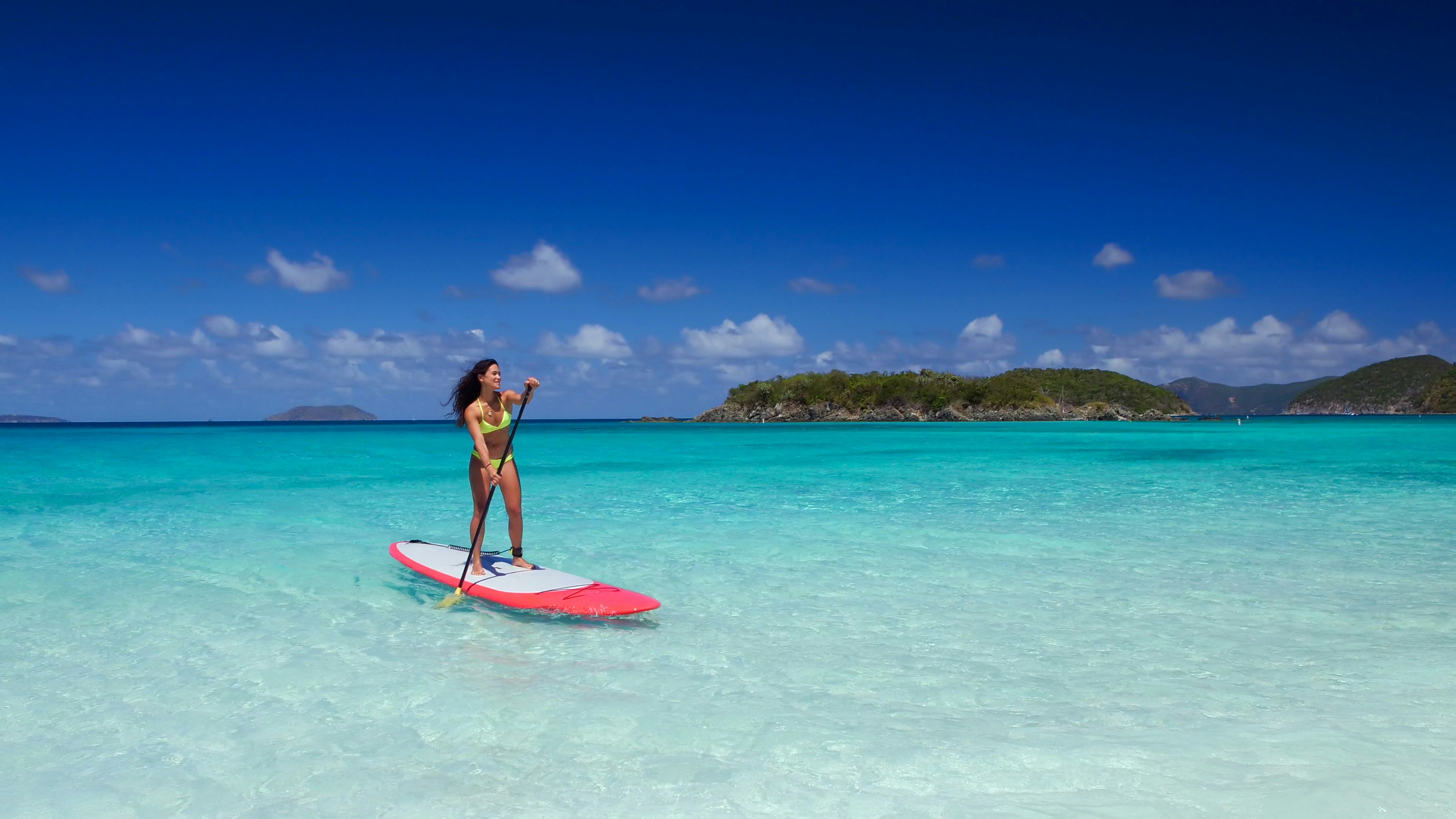 A young woman is paddle boarding off the coast of the US Virgin Islands