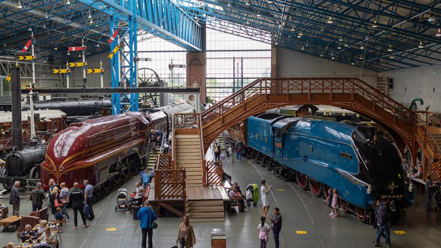 Tourists walk around a red and blue locomotive at the National Railway Museum