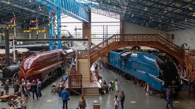 Tourists walk around a red and blue locomotive at the National Railway Museum