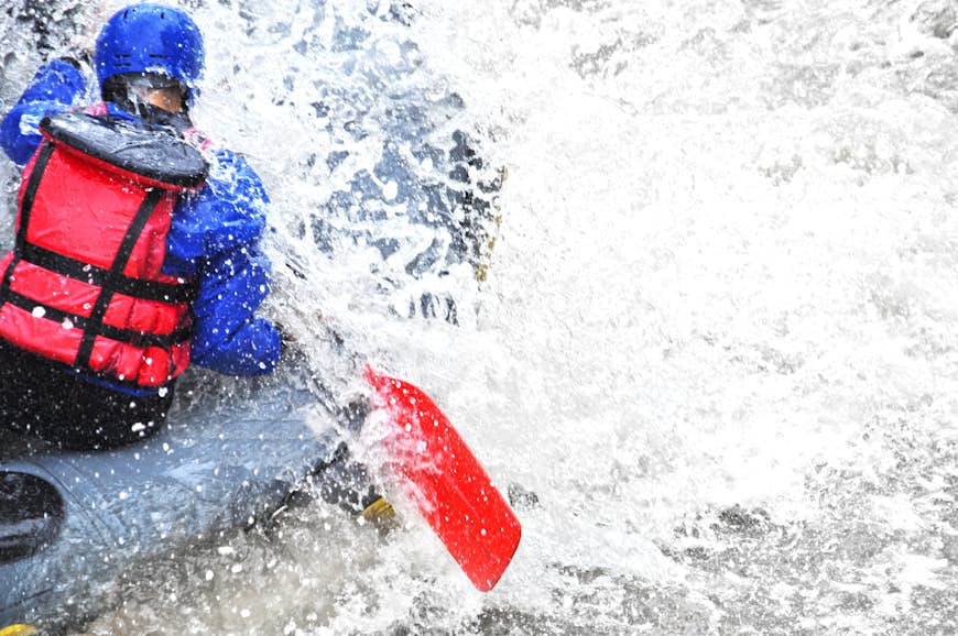 A woman paddles while white water rafting.