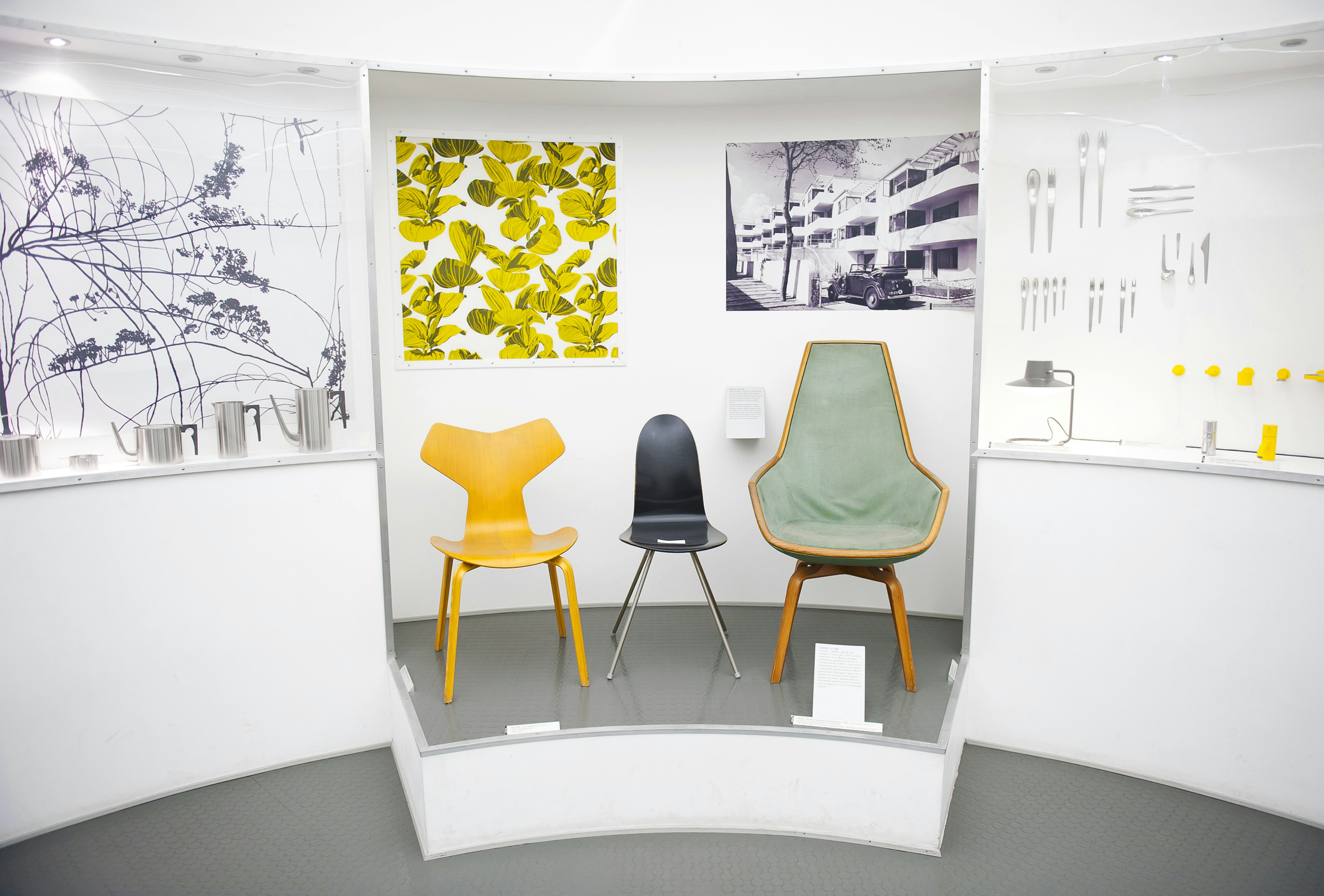 An exhibit of modern-style chairs framed by modern paintings at the Designmuseum Danmark