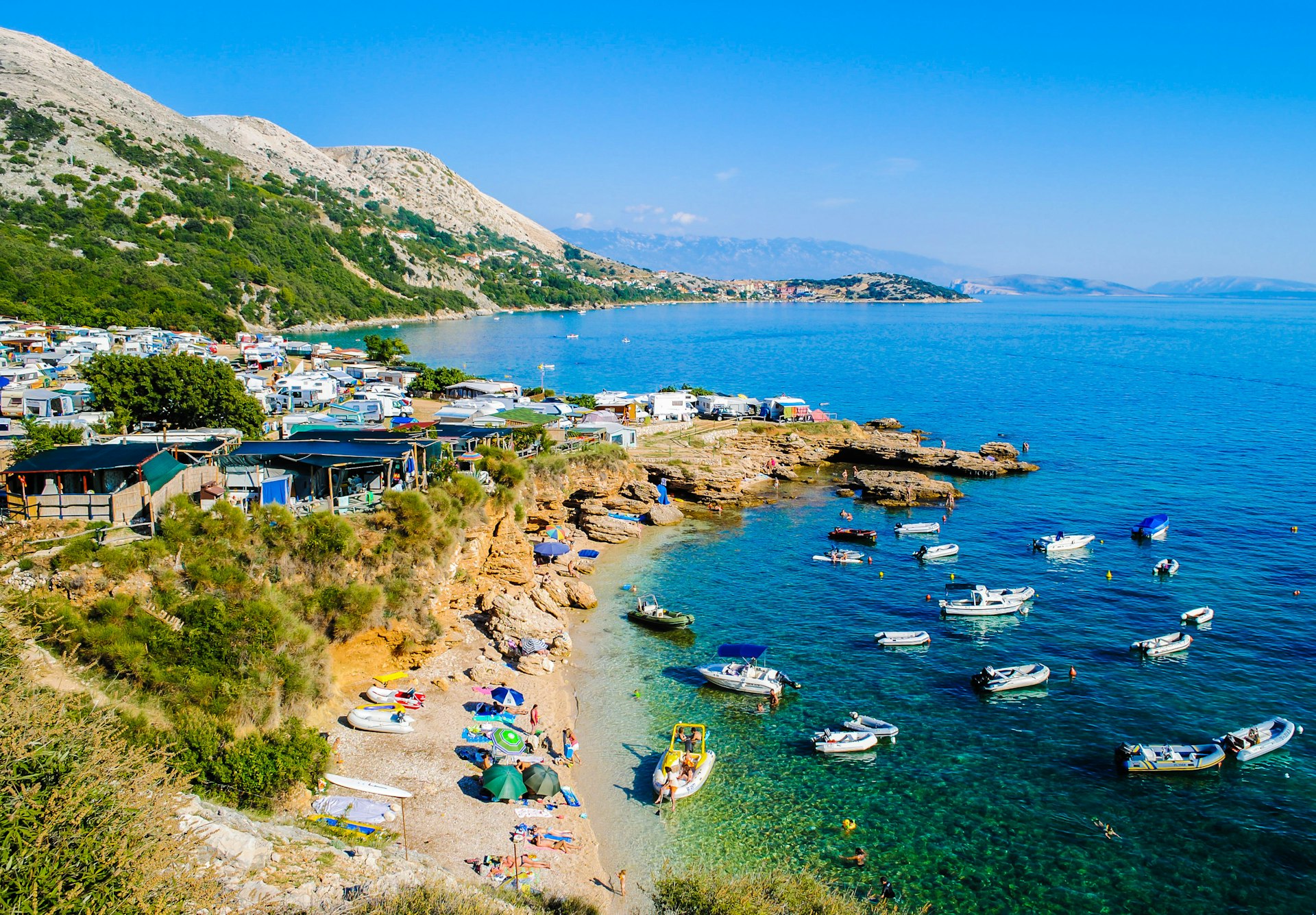 A views of sunbathers and boats at Stara Baska beach on Krk island, Croatia