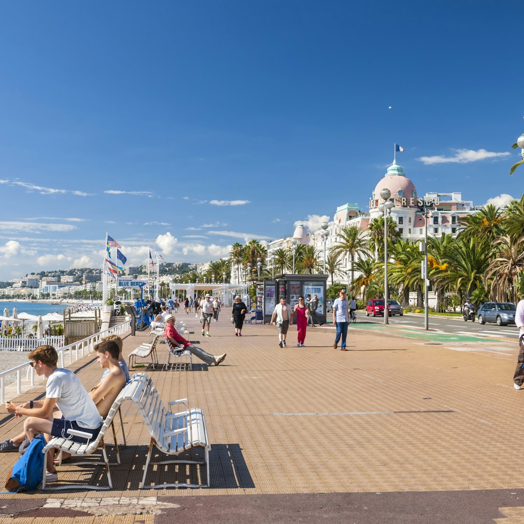 OCTOBER 2, 2014: People enjoying sunny weather at English promenade (Promenade des Anglais), with the Hotel Negresco in the background.