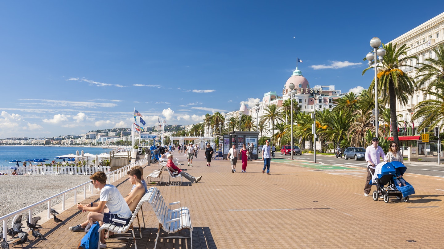 OCTOBER 2, 2014: People enjoying sunny weather at English promenade (Promenade des Anglais), with the Hotel Negresco in the background.