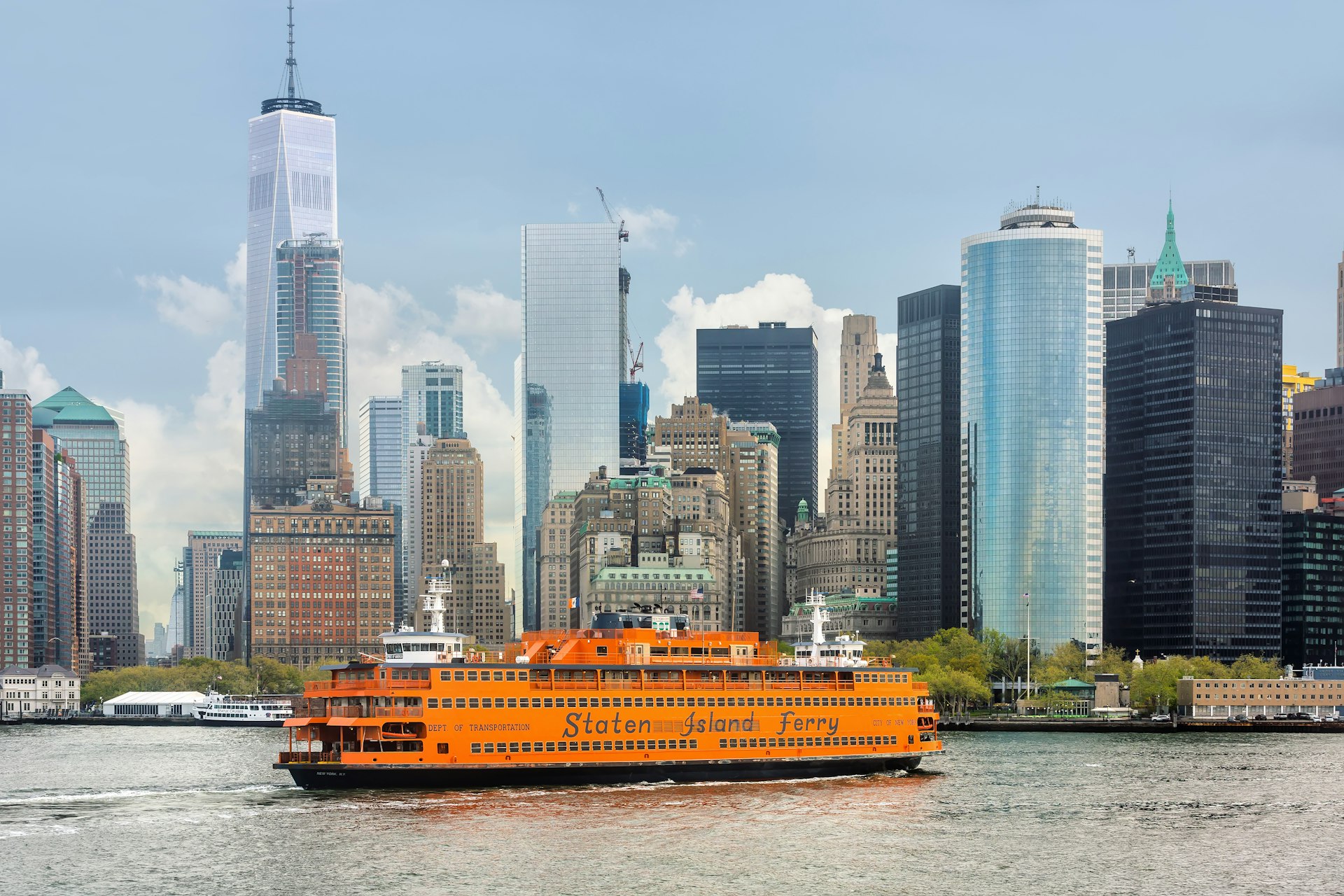 An orange boat of the Staten Island Ferry in New York Harbor against Lower Manhattan skyscrapers, New York City, New York, USA