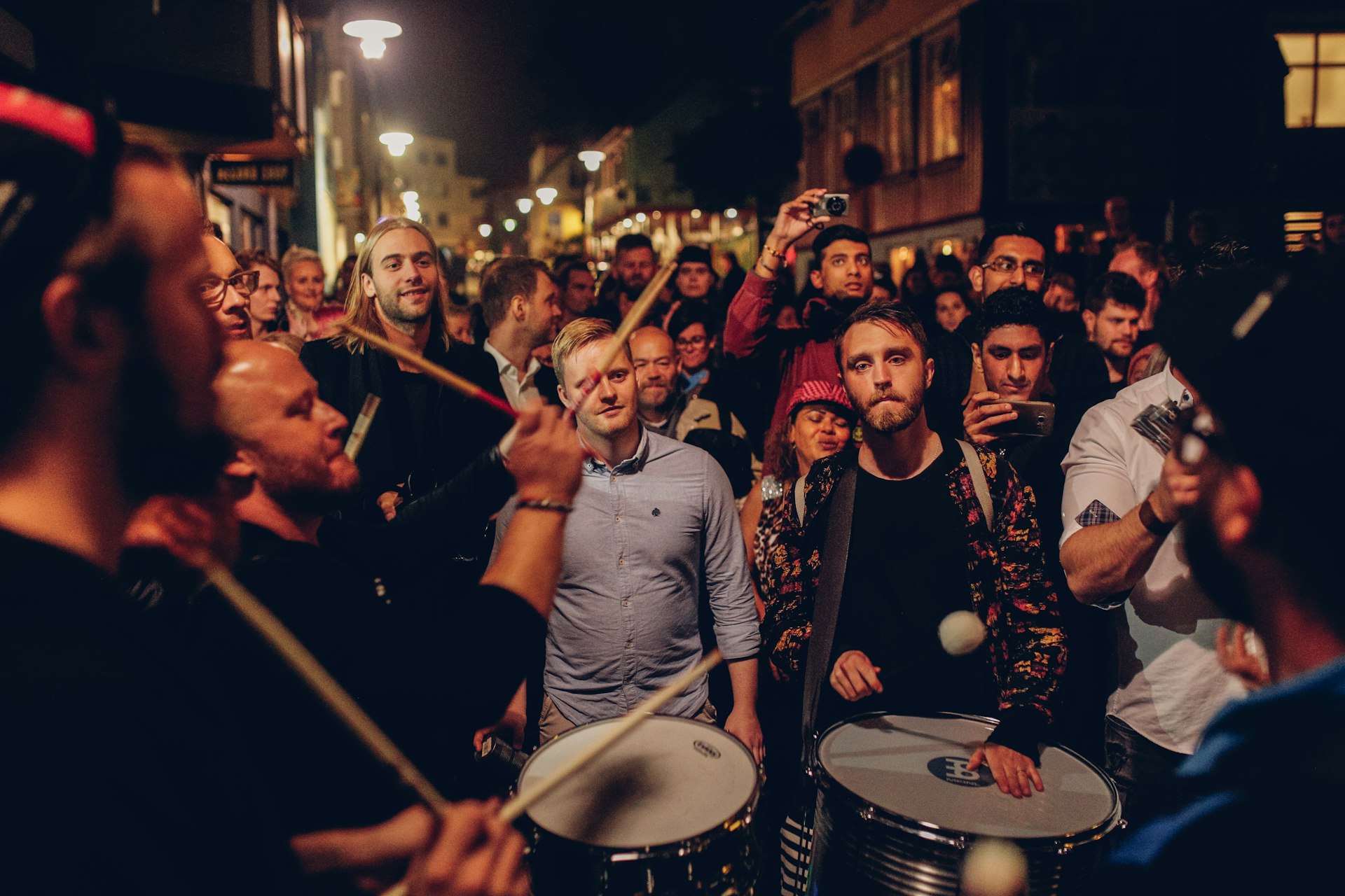 Drummers playing to a crowd of people in the street at night
