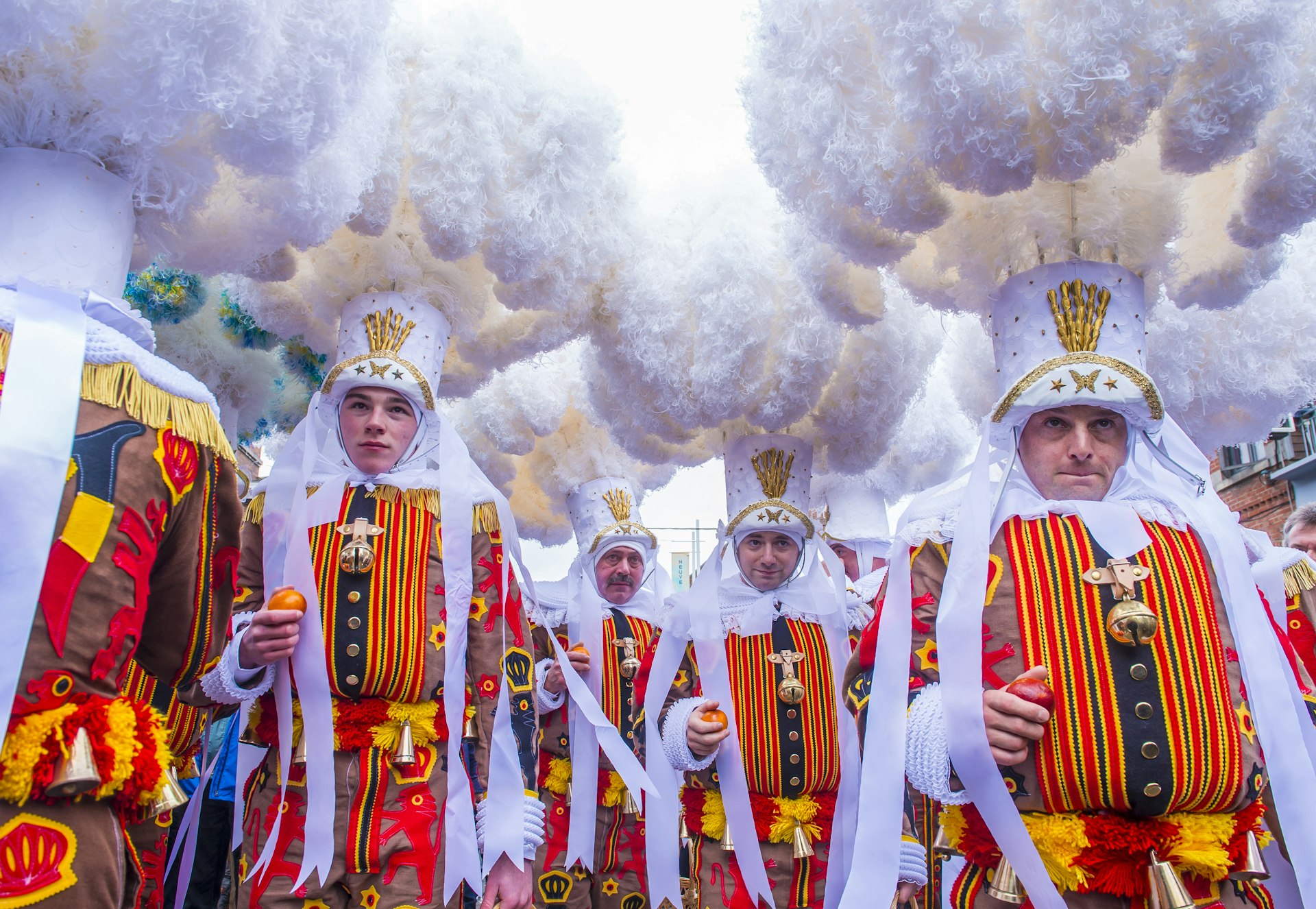 Men in flamboyant costumes march in a parade at a carnival