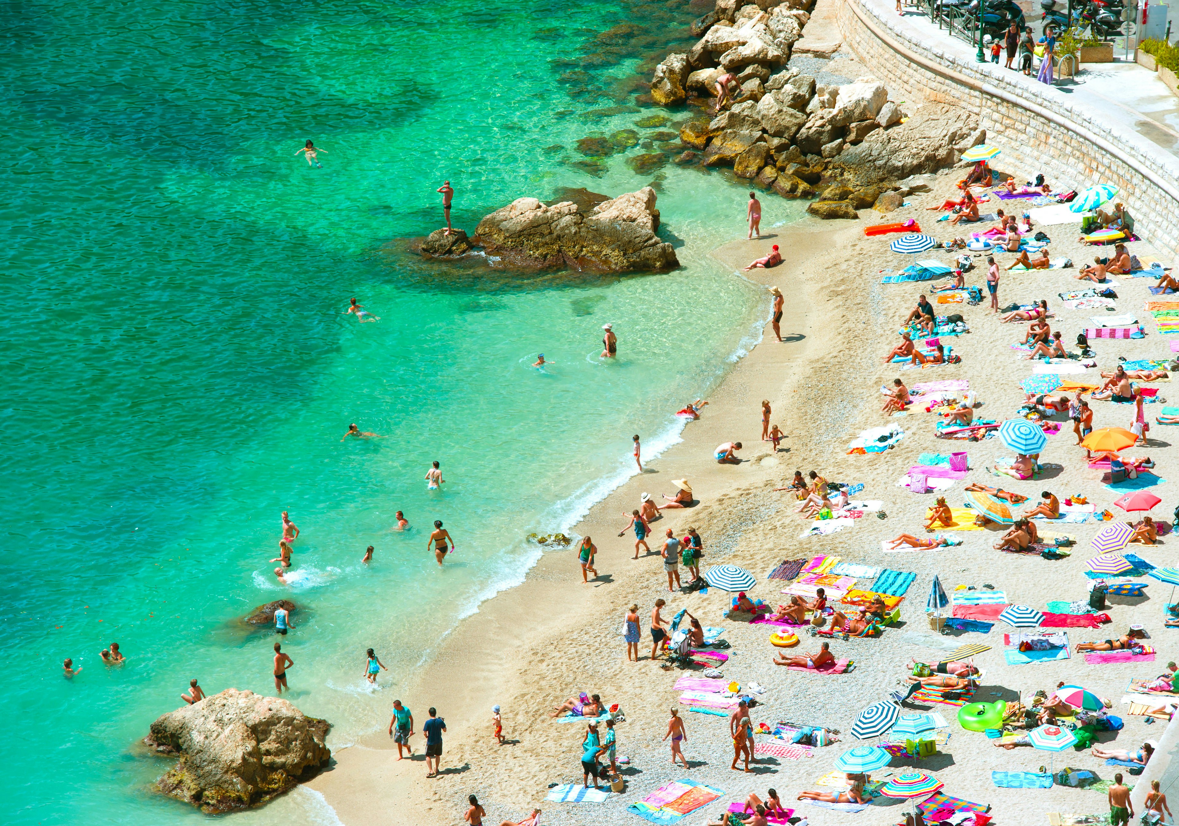 Sunseekers line the pebble beach in Nice