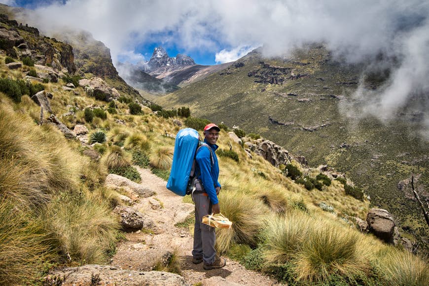 A guide on the trail to the summit of Mt Kenya with clouds behind