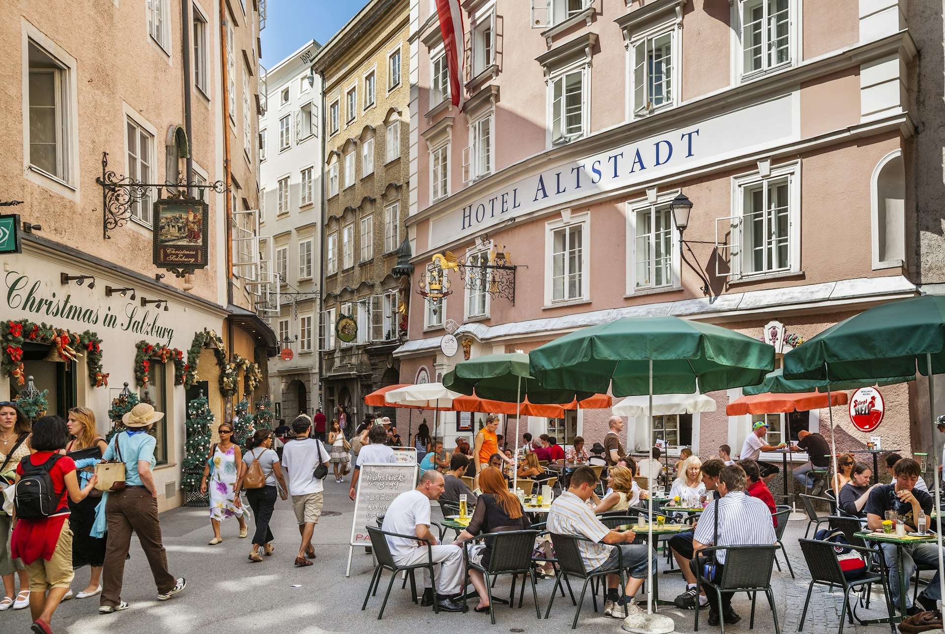 People sit at outdoor dining tables on the pedestrianized street of Salzburg's Old Town
