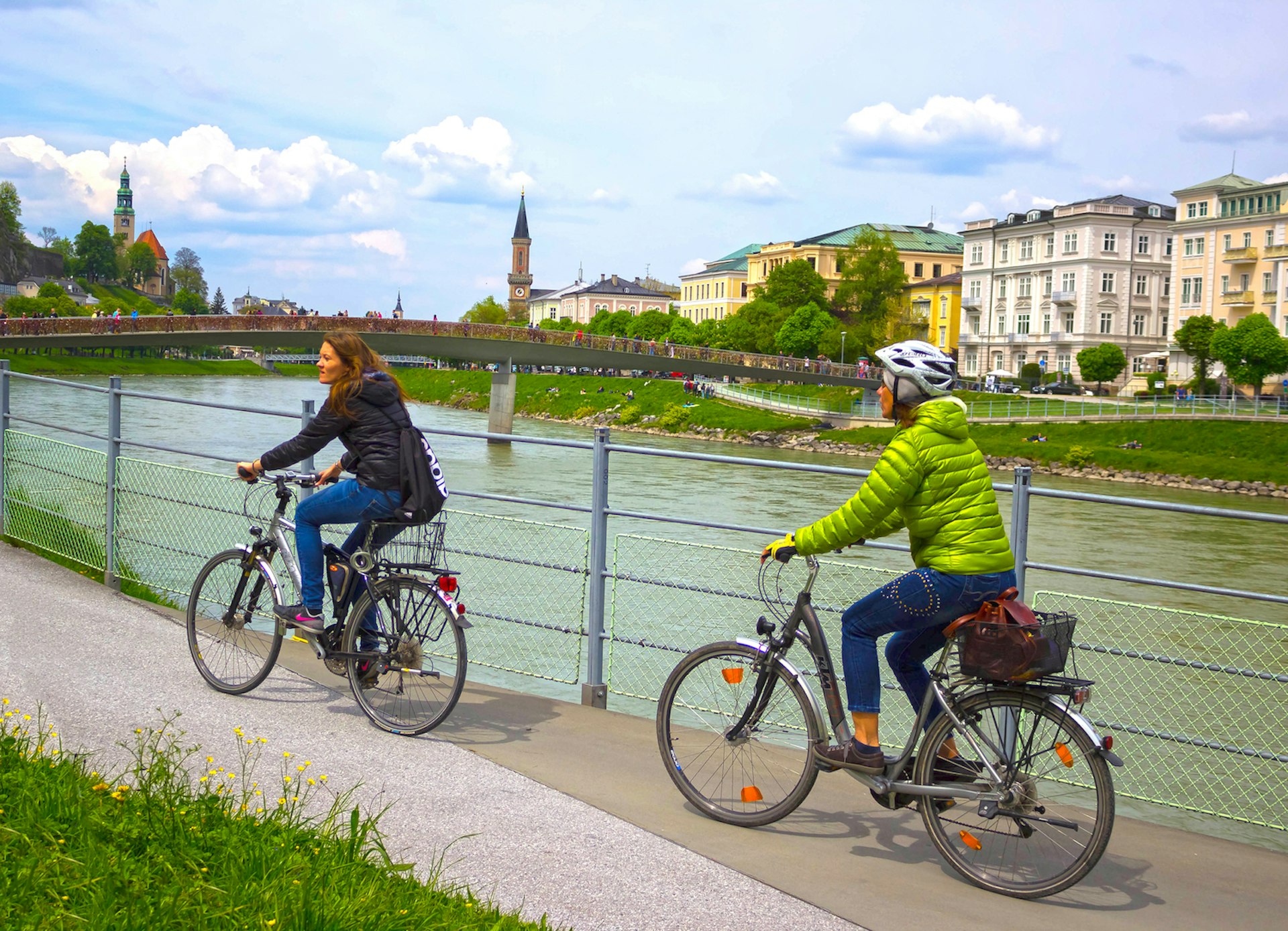Two women on bicycles on the embankment of the Salzach River in Salzburg, Salzburgerland, Austria, Europe