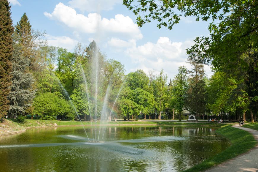 A fountain spraying water into the air in the middle of a pond in the Volksgarten park in Salzburg