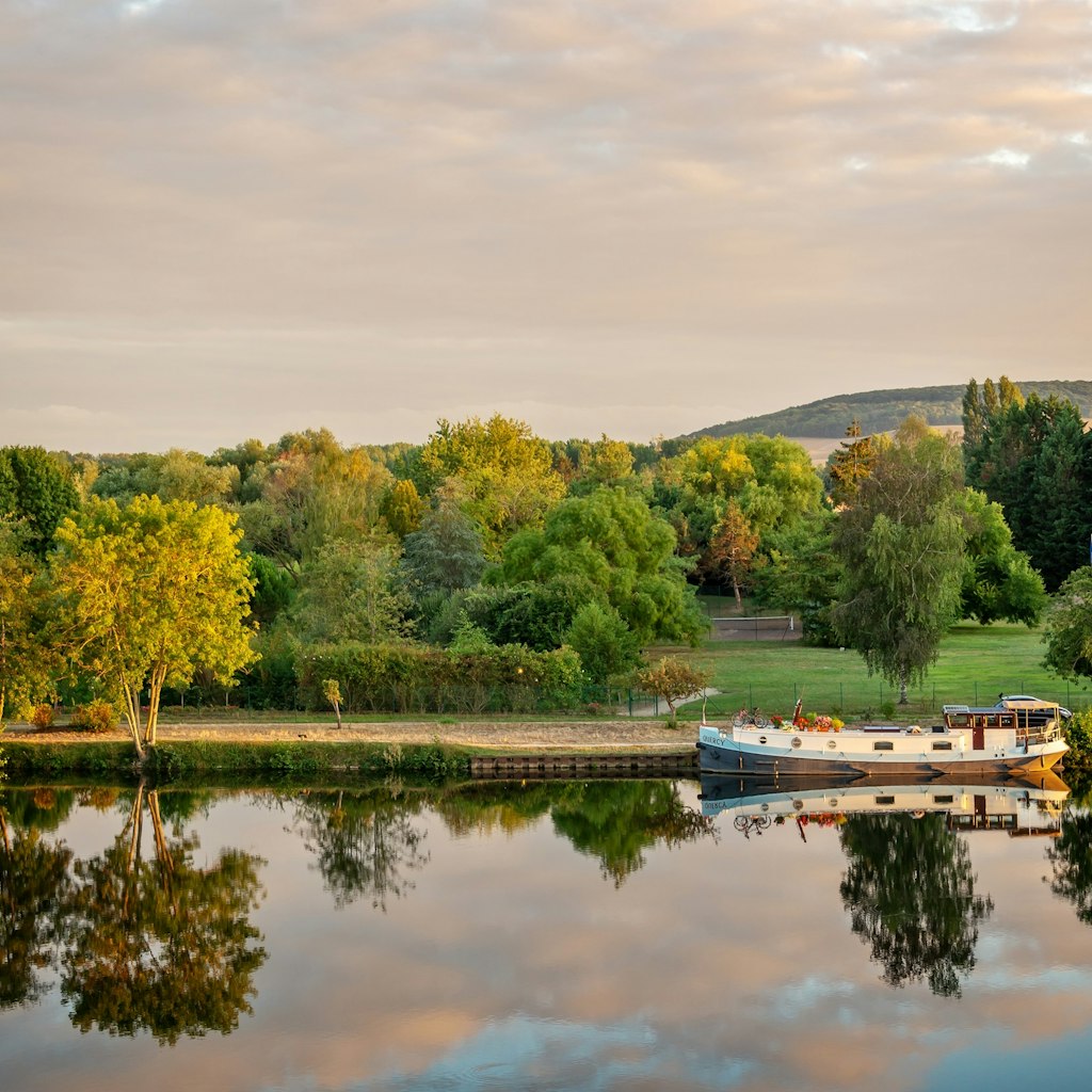 Boat on the Yonne river with reflections at sunset near Joigny  in Burgundy, France.