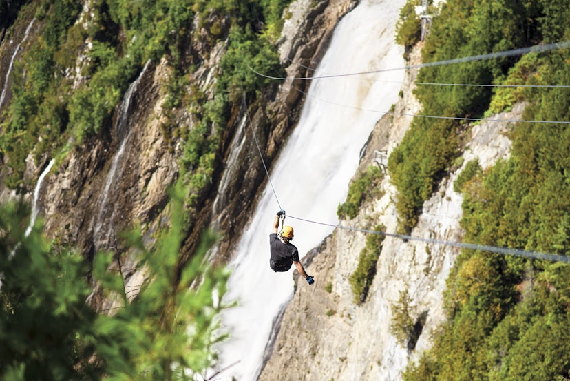 A man descending the double zip line above the Montmorency Falls