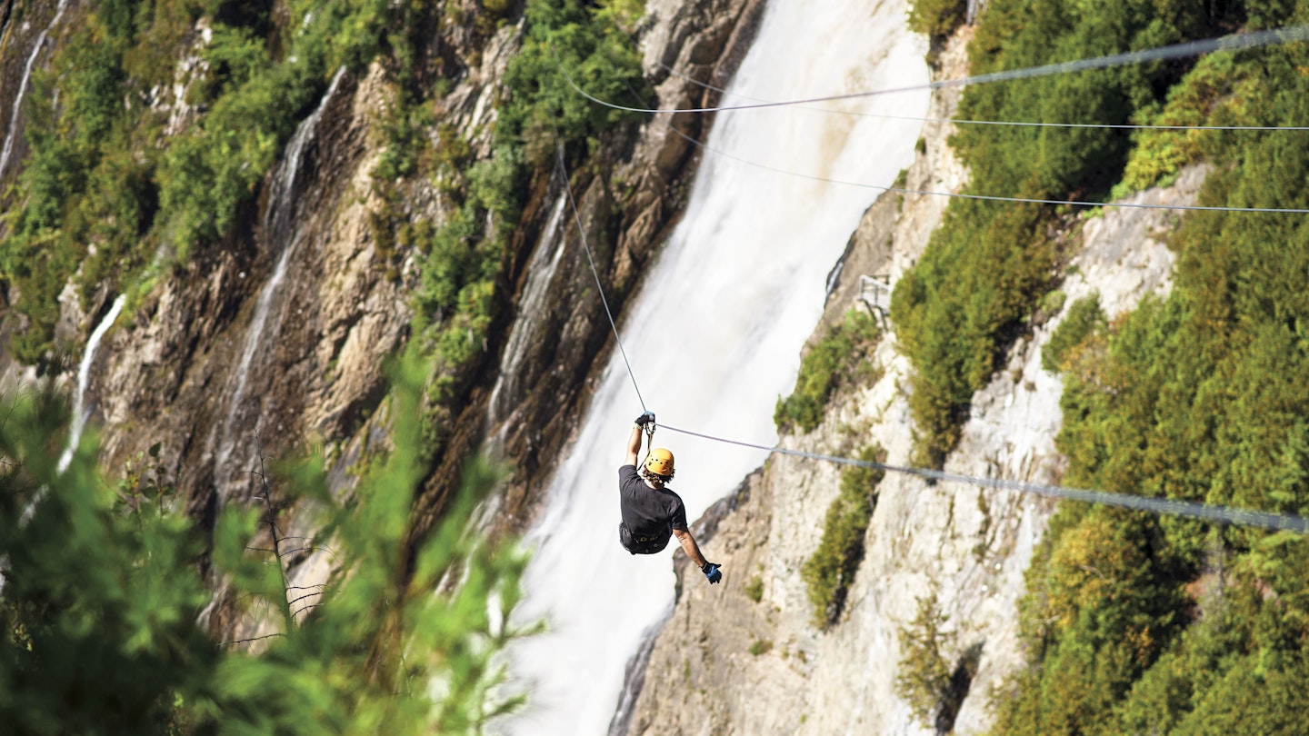 A man descending the double zip line above the Montmorency Falls