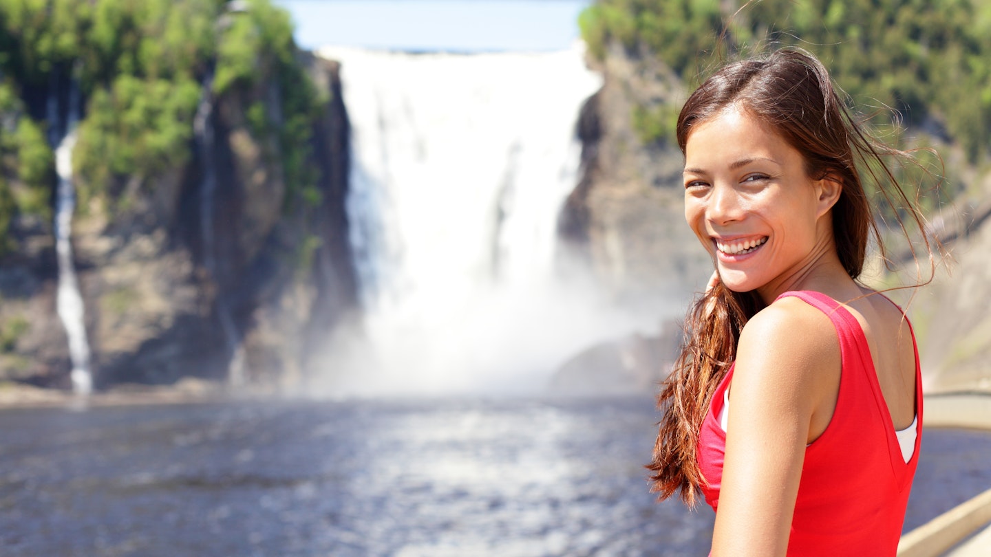 Chute montmorency falls quebec and woman tourist smiling happy in red summer dress looking at; Shutterstock ID 130214375; your: Tasmin Waby; gl: 65050; netsuite: Online Editorial; full: Demand Project