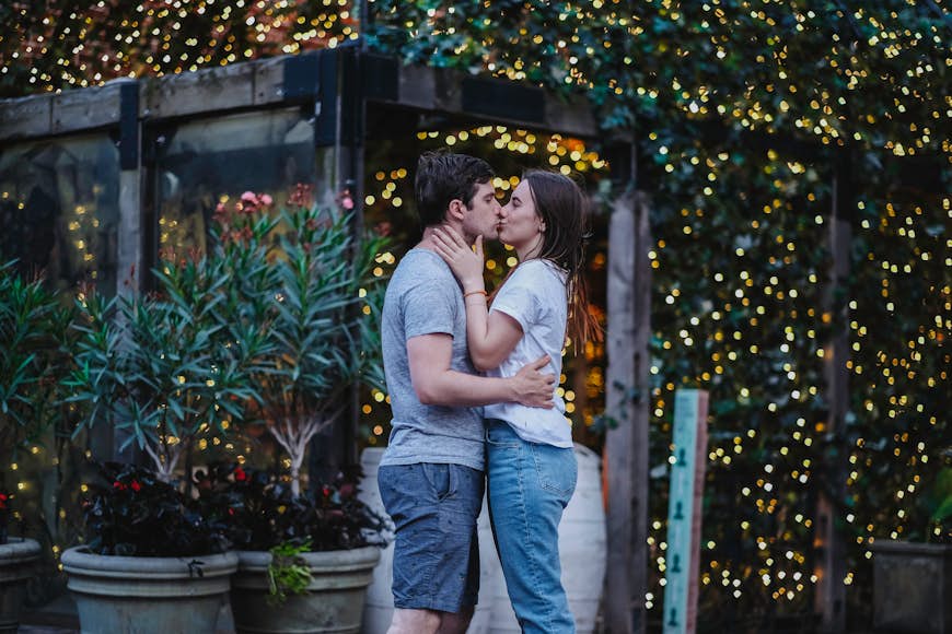 A couple kisses against lights on a facade in the Distillery District, Toronto, Ontario, Canada