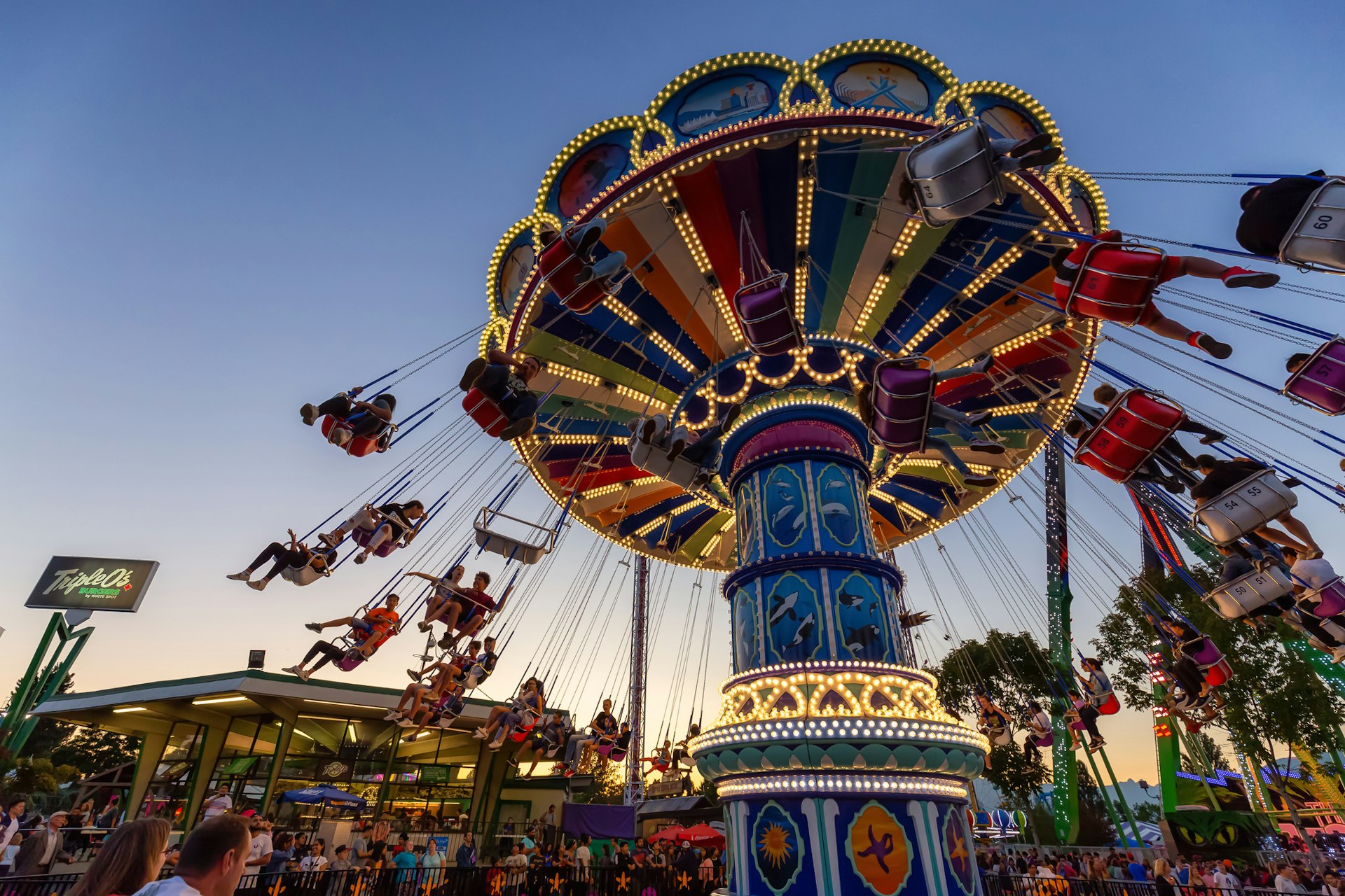 A swing carousel in motion, with children riding in the swing seats