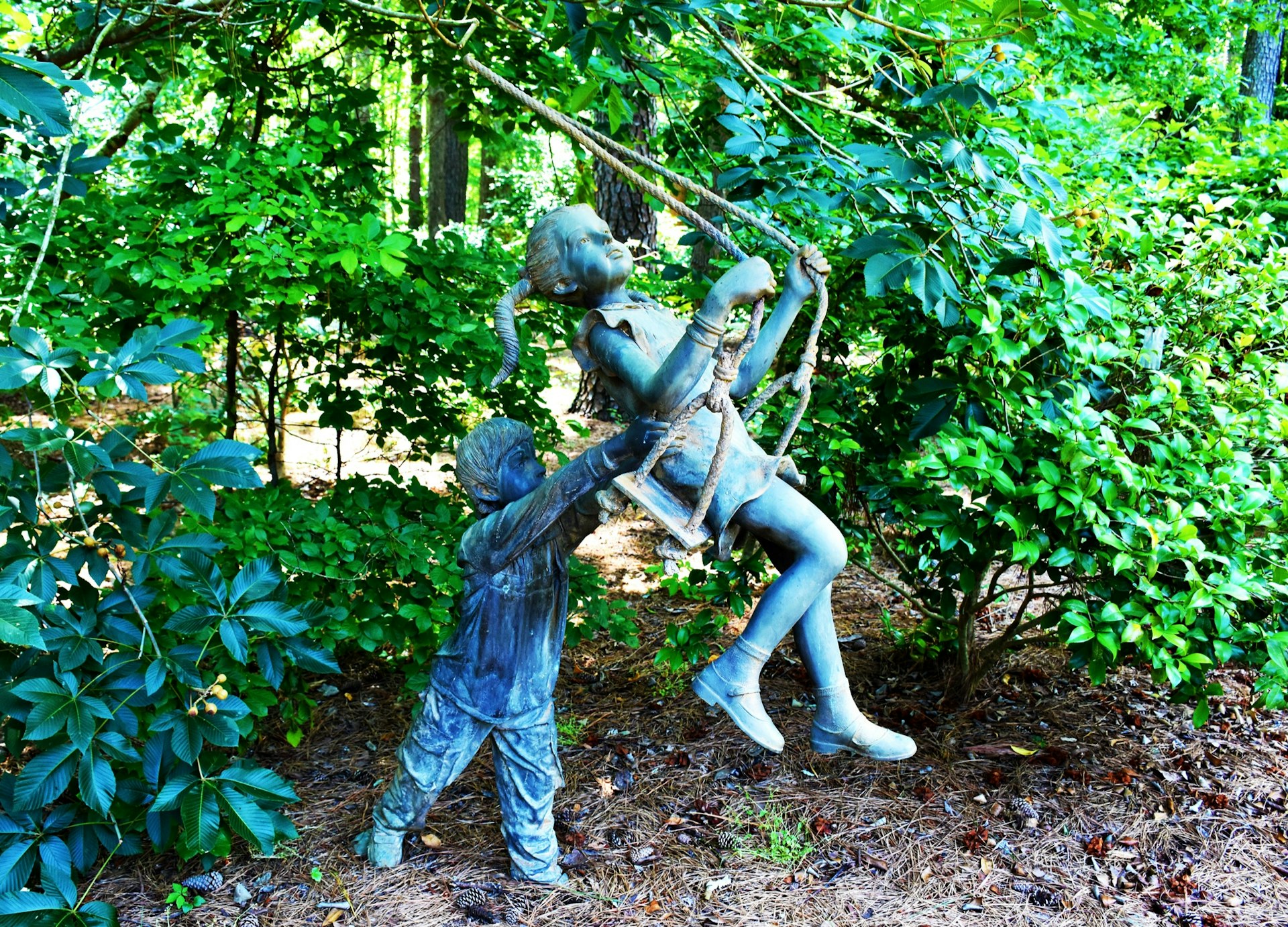 Statue of a young boy pushing a young girl on a swing at the Cape Fear Botanical Garden in Fayetteville, North Carolina. 