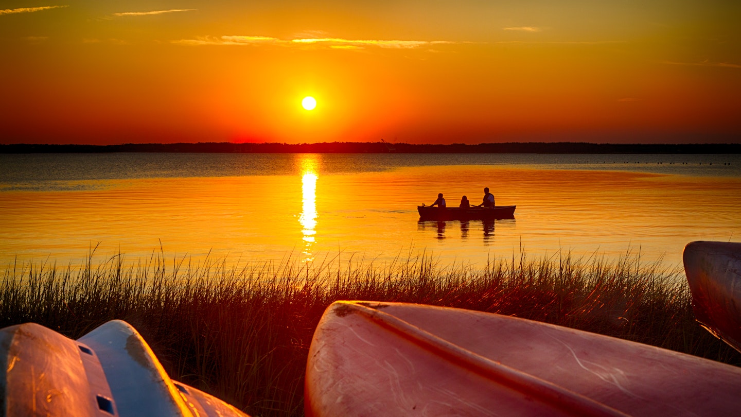 A trio of people glide across the Cape Fear River on a canoe during sunset in Fayetteville, North Carolina. 