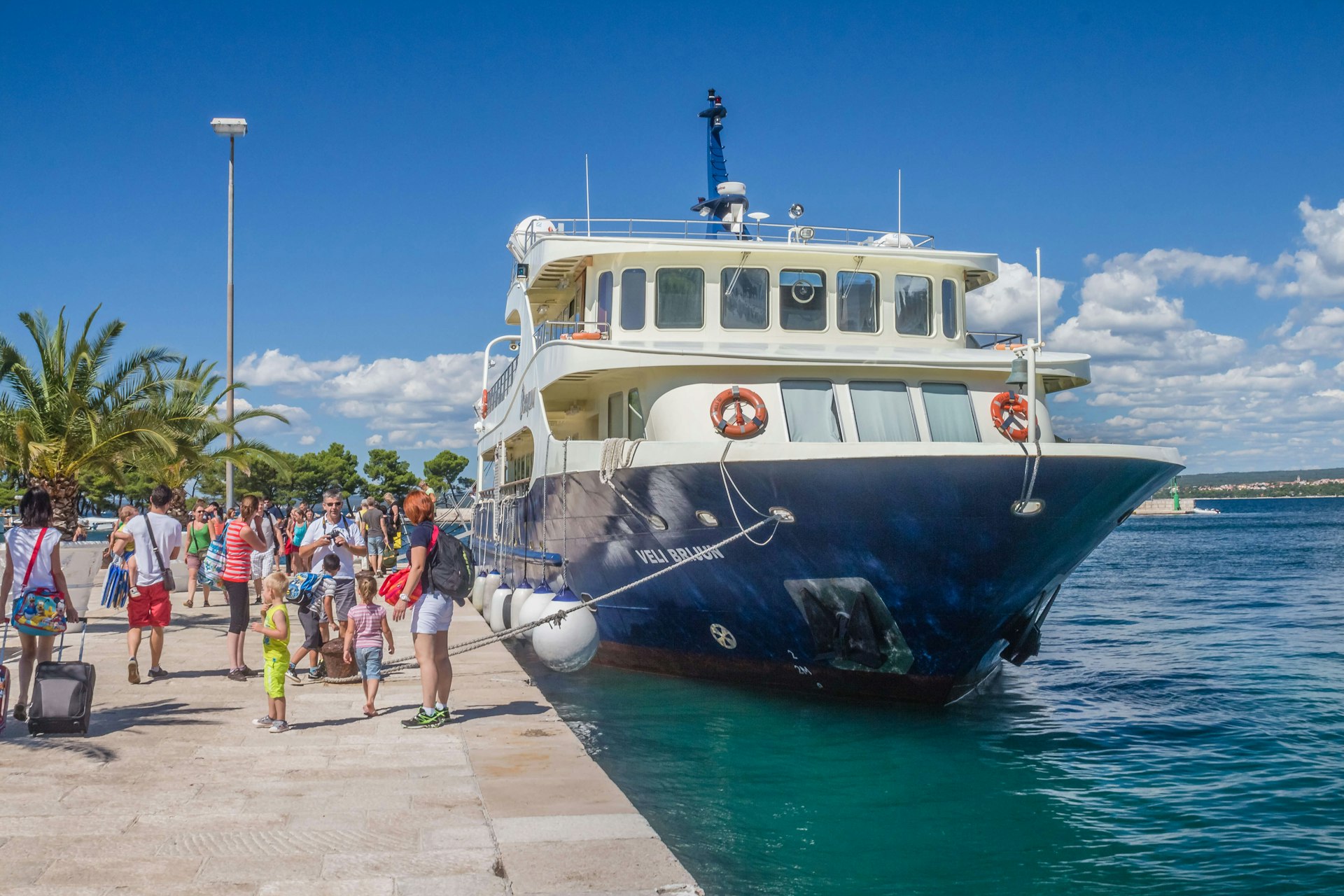 People gathered on a pier near a boat in Brijuni National Park, Croatia, on a bright sunny day