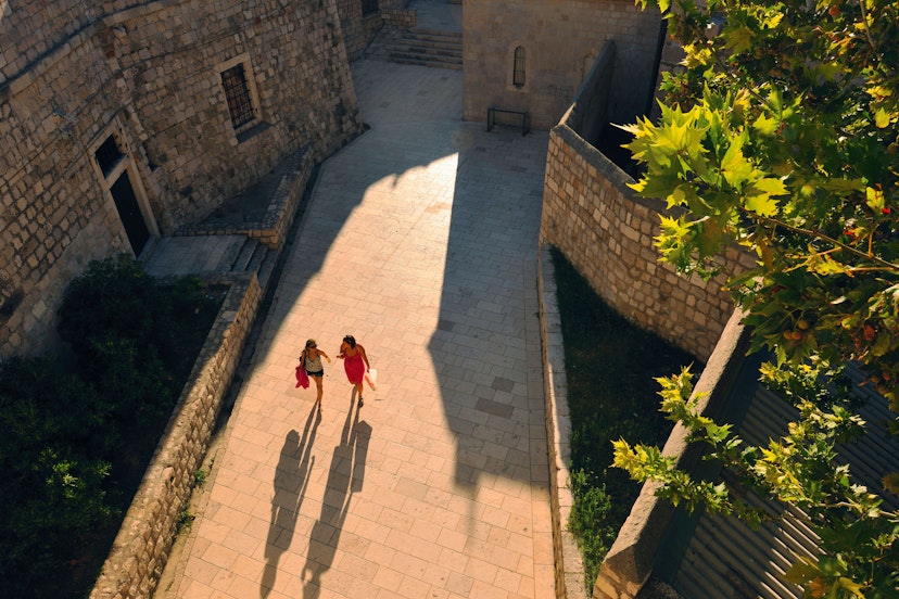 Two people walking through Dubrovnik and casting long shadows, seen from above